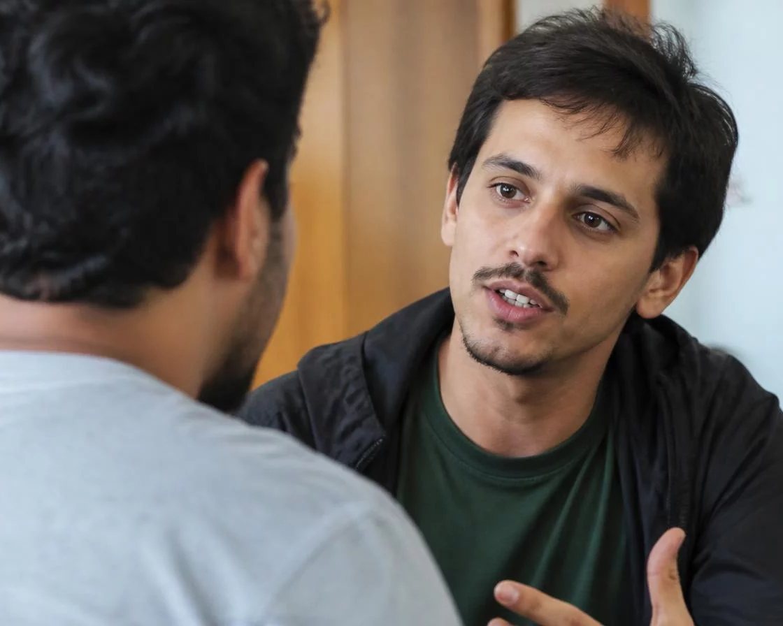 Pessoa em pé diante da turma sustentando um argumento com as anotações na mão